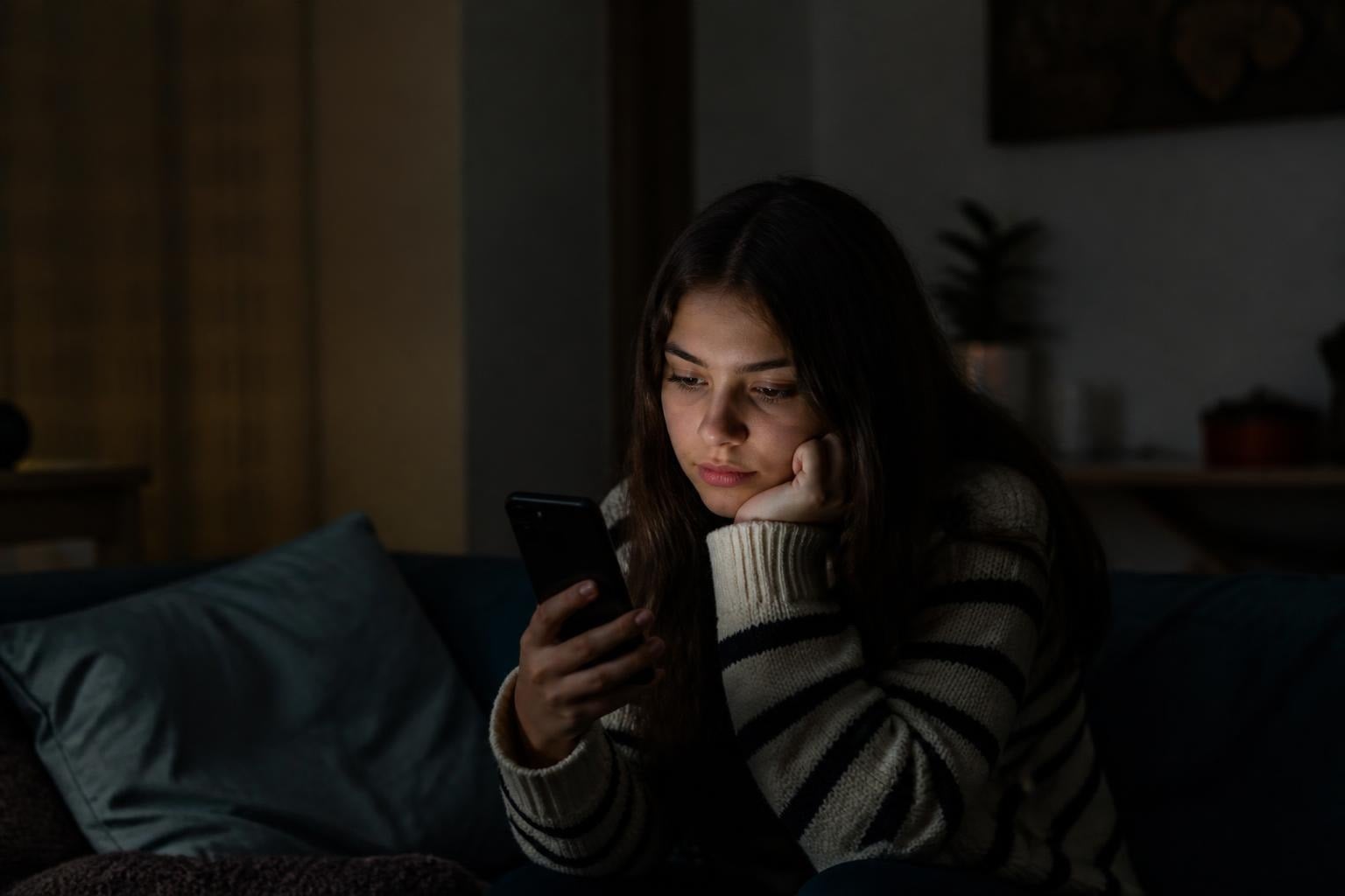 Woman resting her head on her hand while looking at her phone
